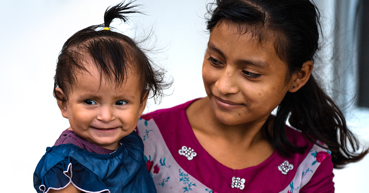 A young mother smiles at her child who has grown to be healthy.