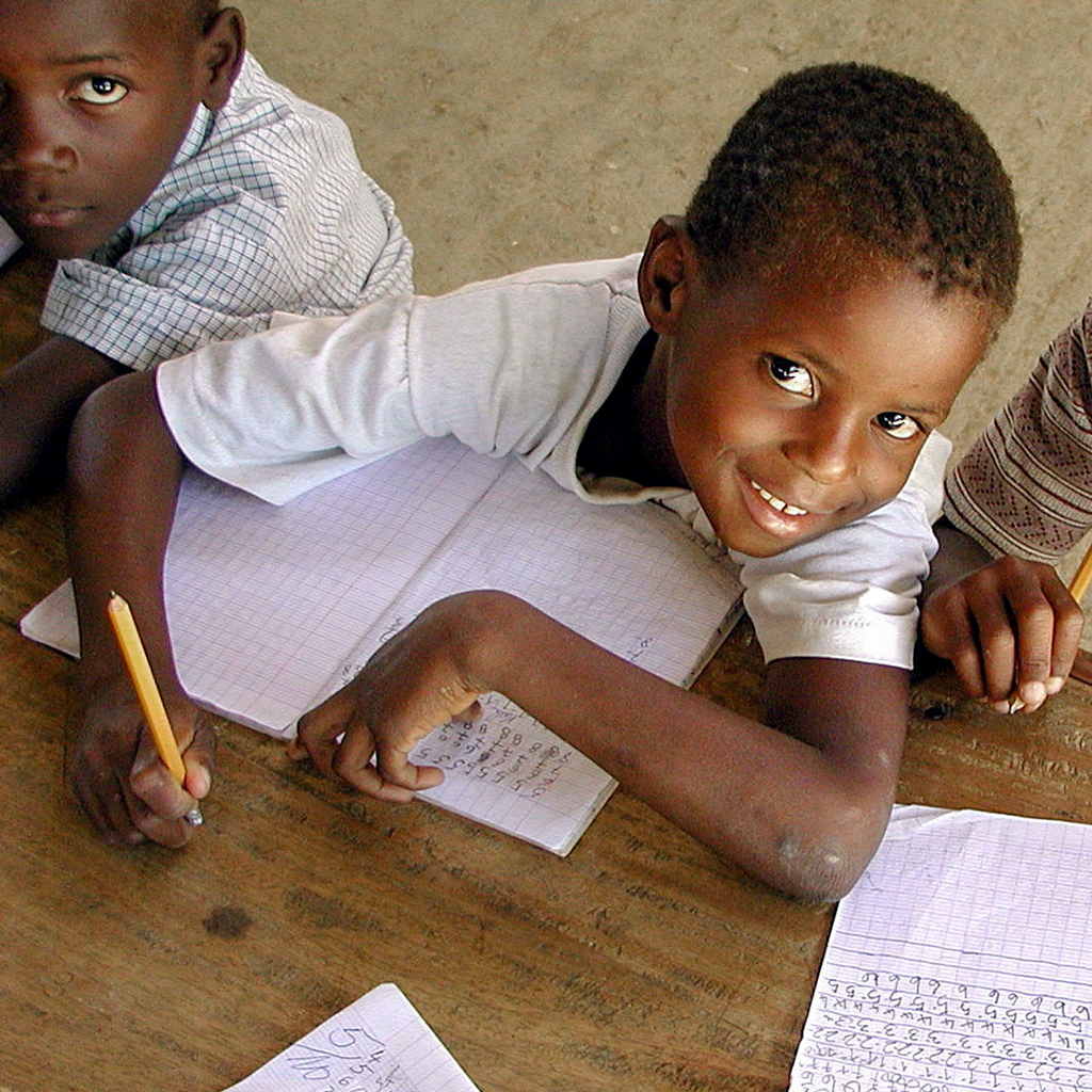 A school boy smiles while he works on schoolwork