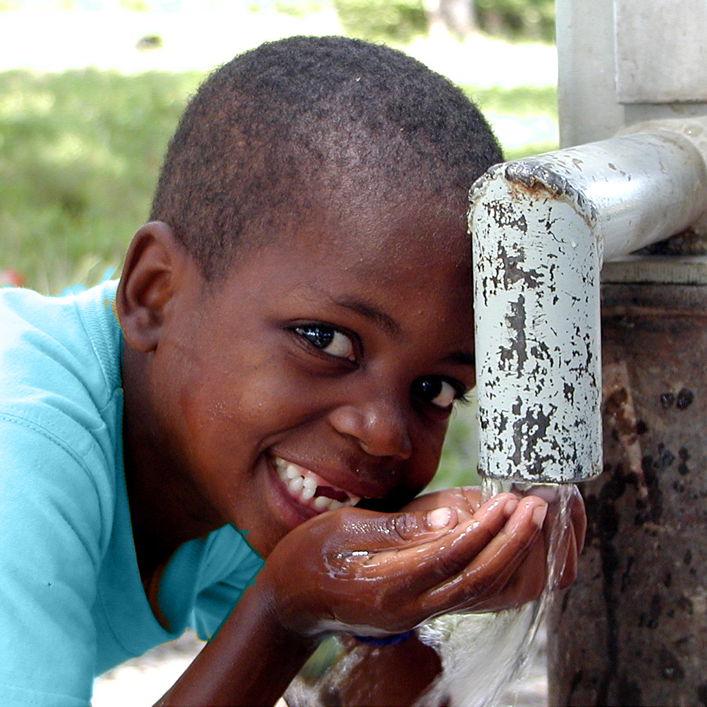 A boy drinks from a water well