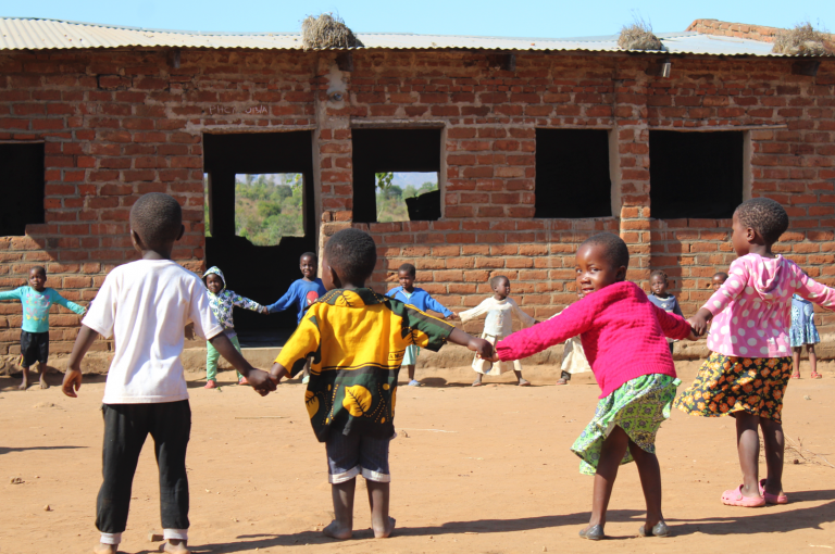 Children stand in a circle holding hands