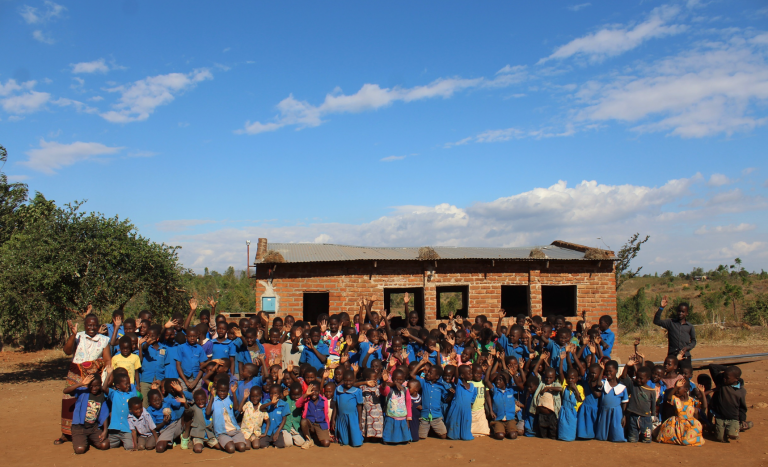 A large group of people smile and wave