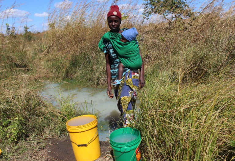 A woman carries her baby and buckets of unsafe water