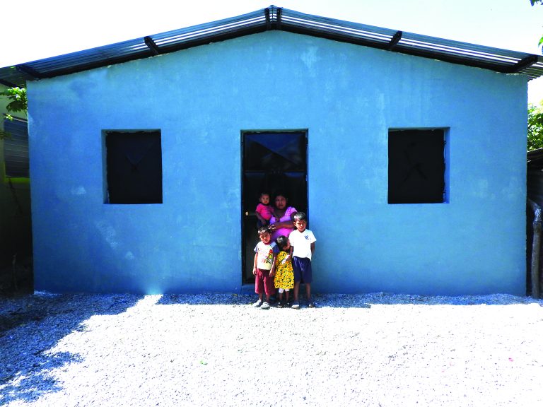 A family stands inside the doorway of their new home