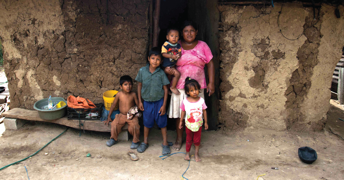 A Family stands outside their old, dilapidated house