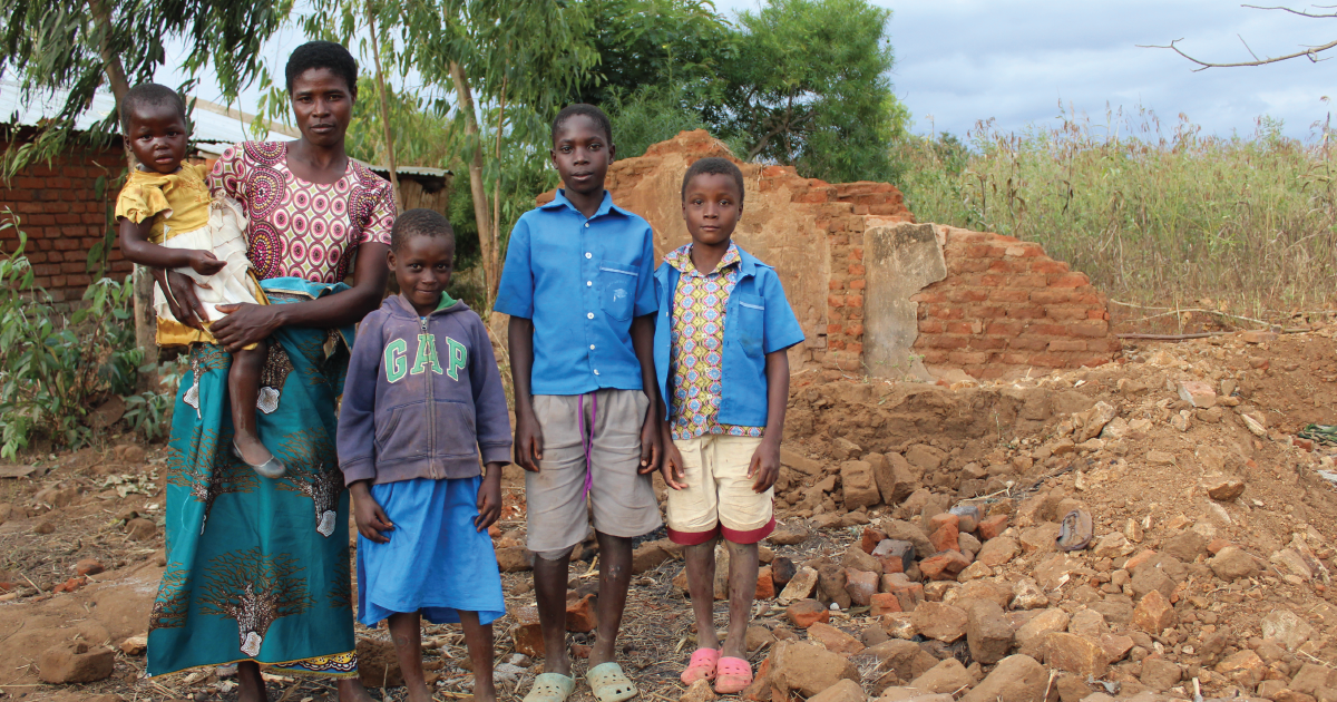 A family stands in front of rubble