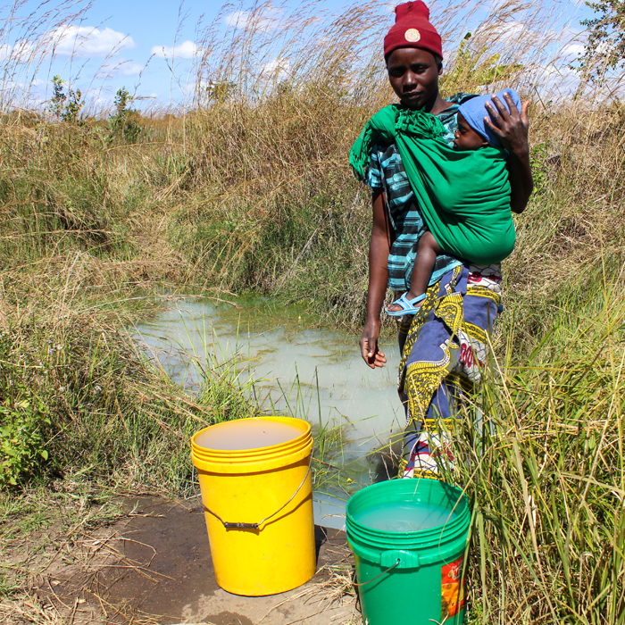 Mother collecting water with her baby