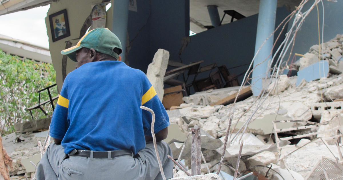 Man sitting in the middle of the rubble after devastating Haiti earthquake in 2010