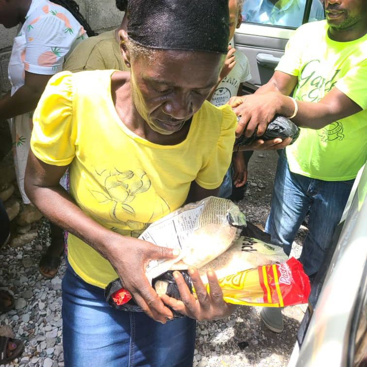 A woman holds packets of food at a food distribution in Haiti