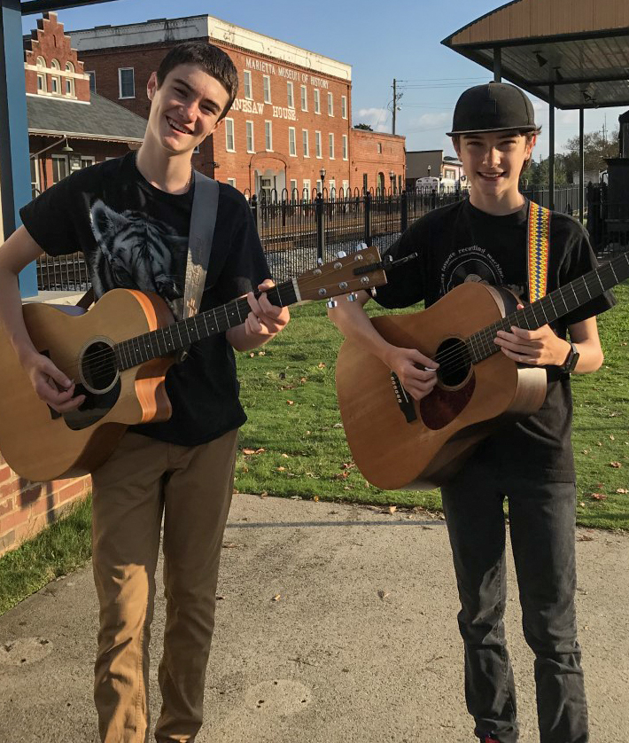 2 boys playing guitar on the street