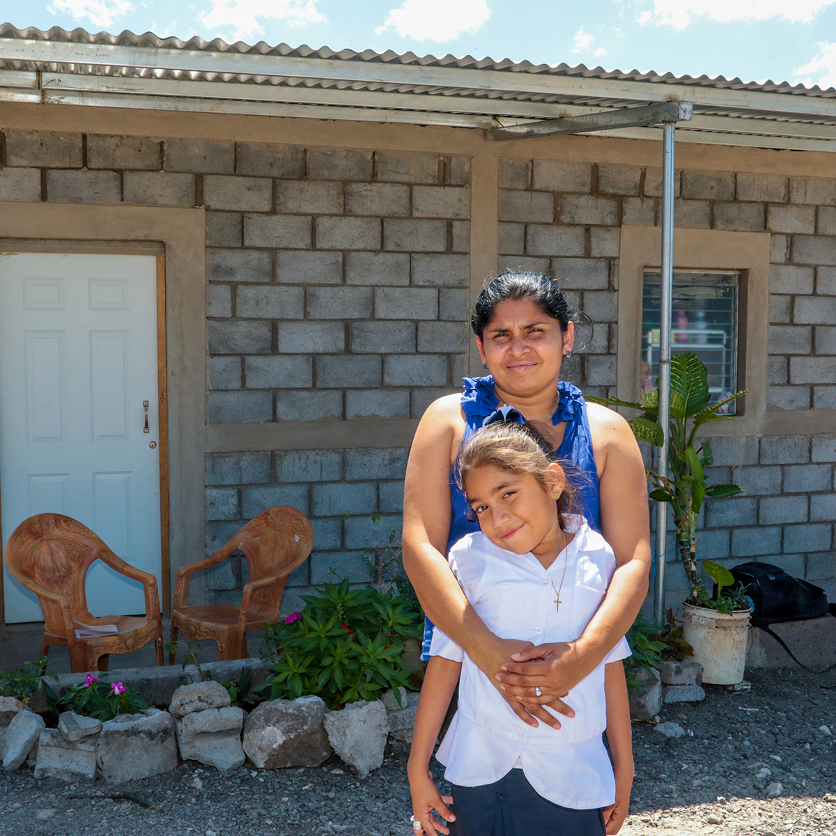 Mother and daughter in front of their new home