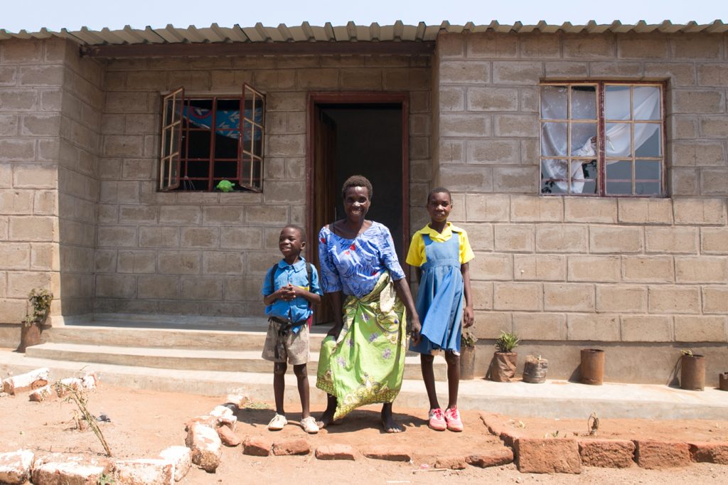 Disabled mother and children in front of their new home
