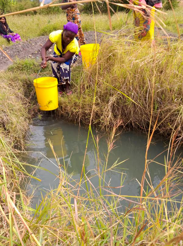 Zambian woman collecting unsafe water from pond