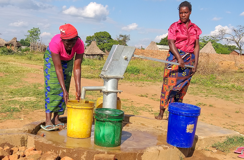 Zambian women pumping water out of new water well