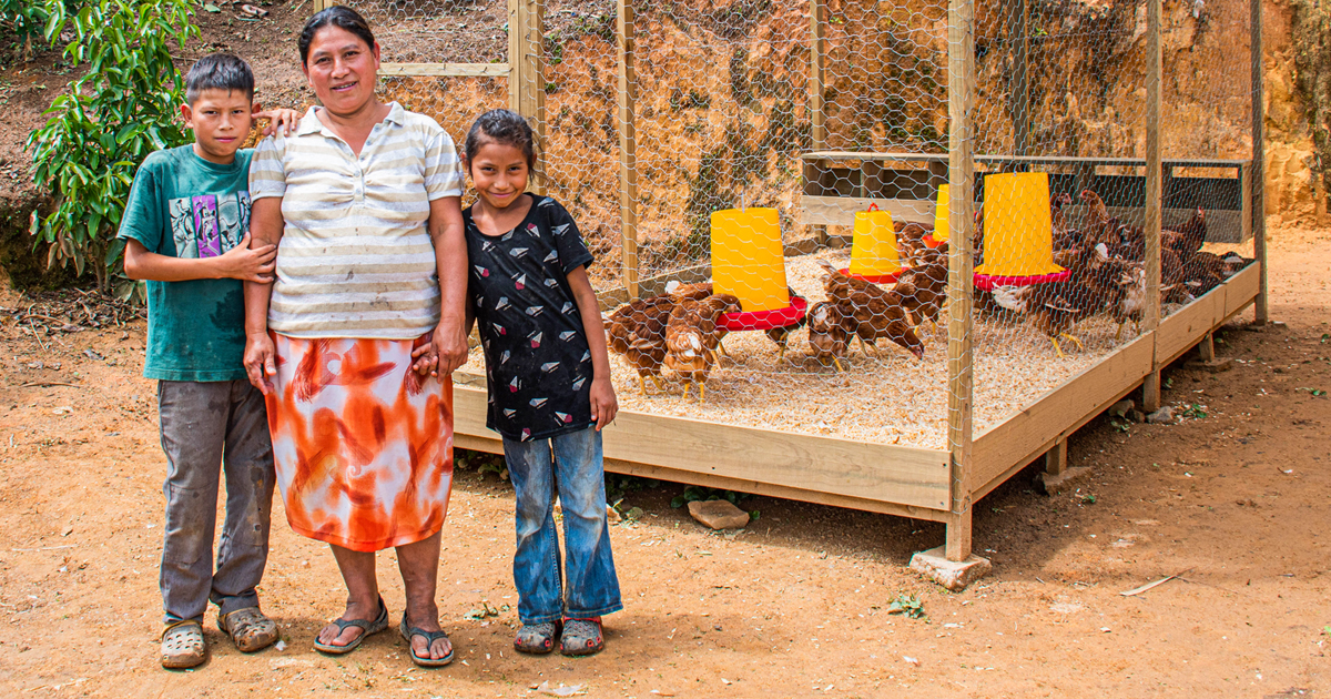 Mother and her two children standing proudly next to their new chicken coop