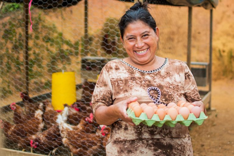 Argelia happy showing a carton of eggs produced by her chickens