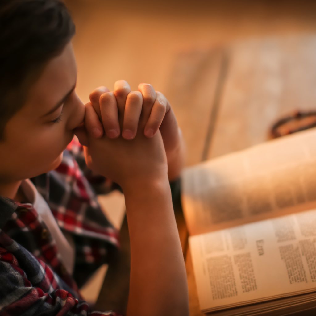 Boy praying with a bible