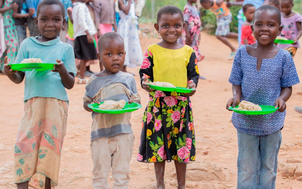 Kids smiling while holding the lunch they have received through the program