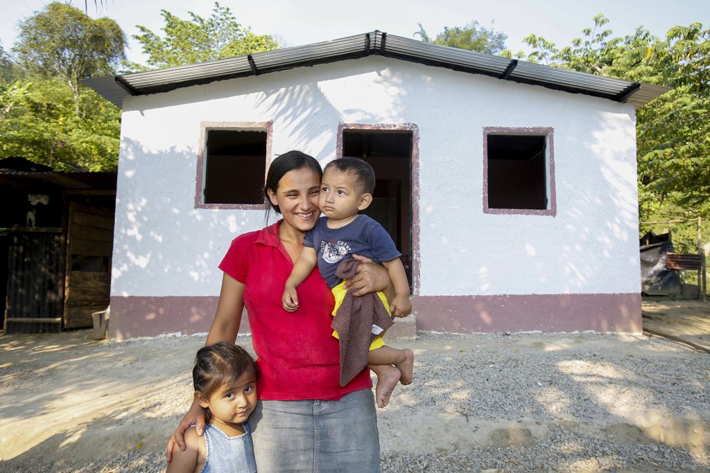 A woman and child stand in front of a new home
