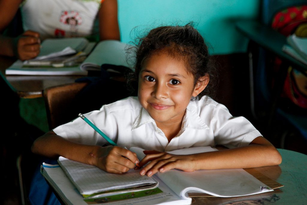A child with learning tools in front of her smiles