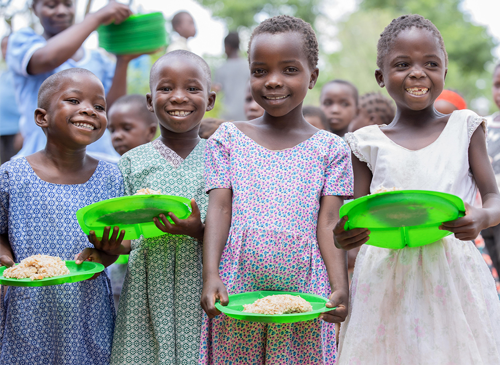 Children smiling after receiving their lunches at the Ambuya Development Center in Malawi