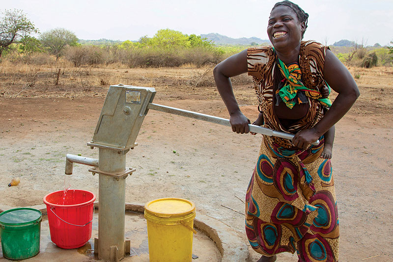 Woman pumping water in Zambian village