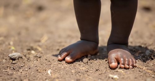 Zambian baby feet standing on soil ground