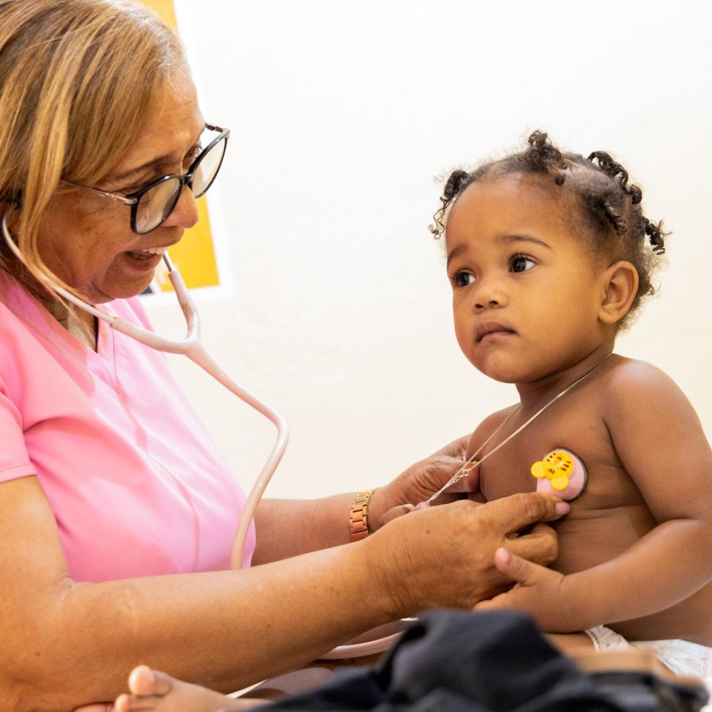 Toddler, a beneficiary of the Thriving Kids Initiative in the Bateys of the Dominican Republic, receiving a check-up from a health professional.