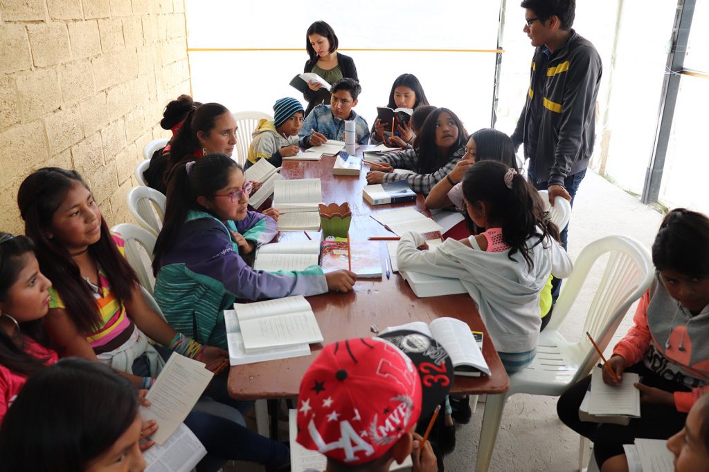 Children gather at a table, learning, as part of the Moses Project in Ecuador.