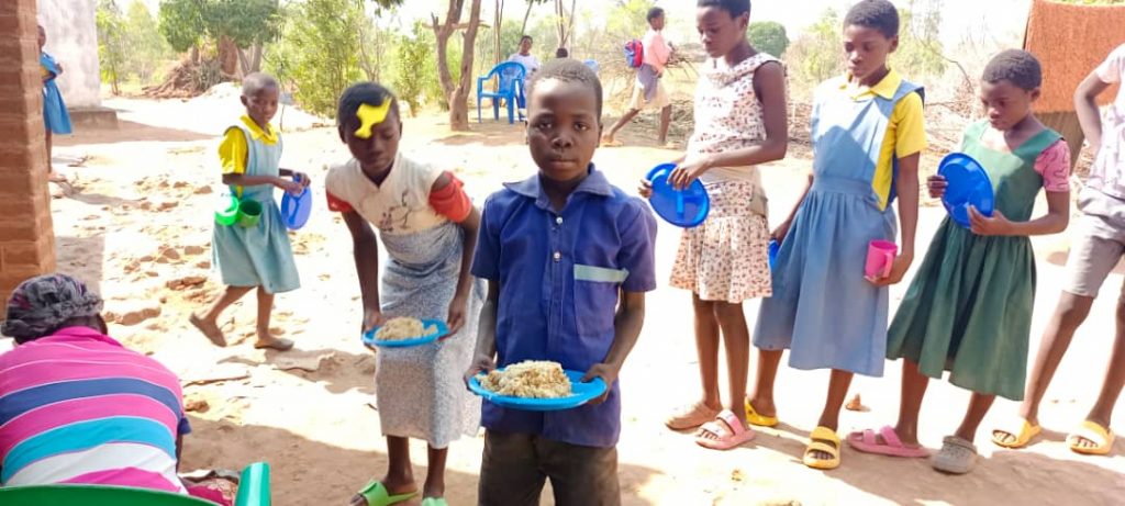 Pemphero with a plate of food in rural Malawi