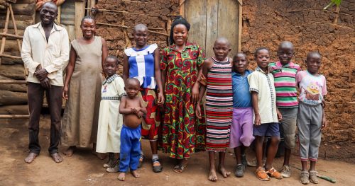 A family gathers in front of a mud-brick and wooden home on the outskirts of Kyakitanga, a rural village in Uganda.
