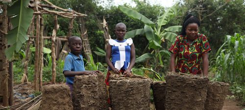 A woman and three children stand in a wooded area of Uganda.