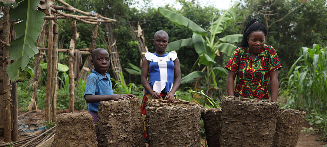 A woman and three children stand in a wooded area of Uganda.