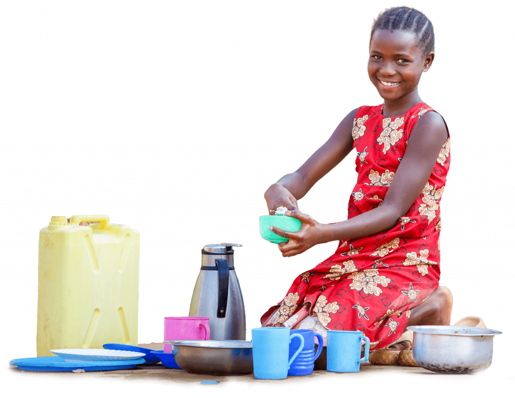 11-year-old Ugandan girl sits on the ground. She smiles directly at the camera while washing dishes.