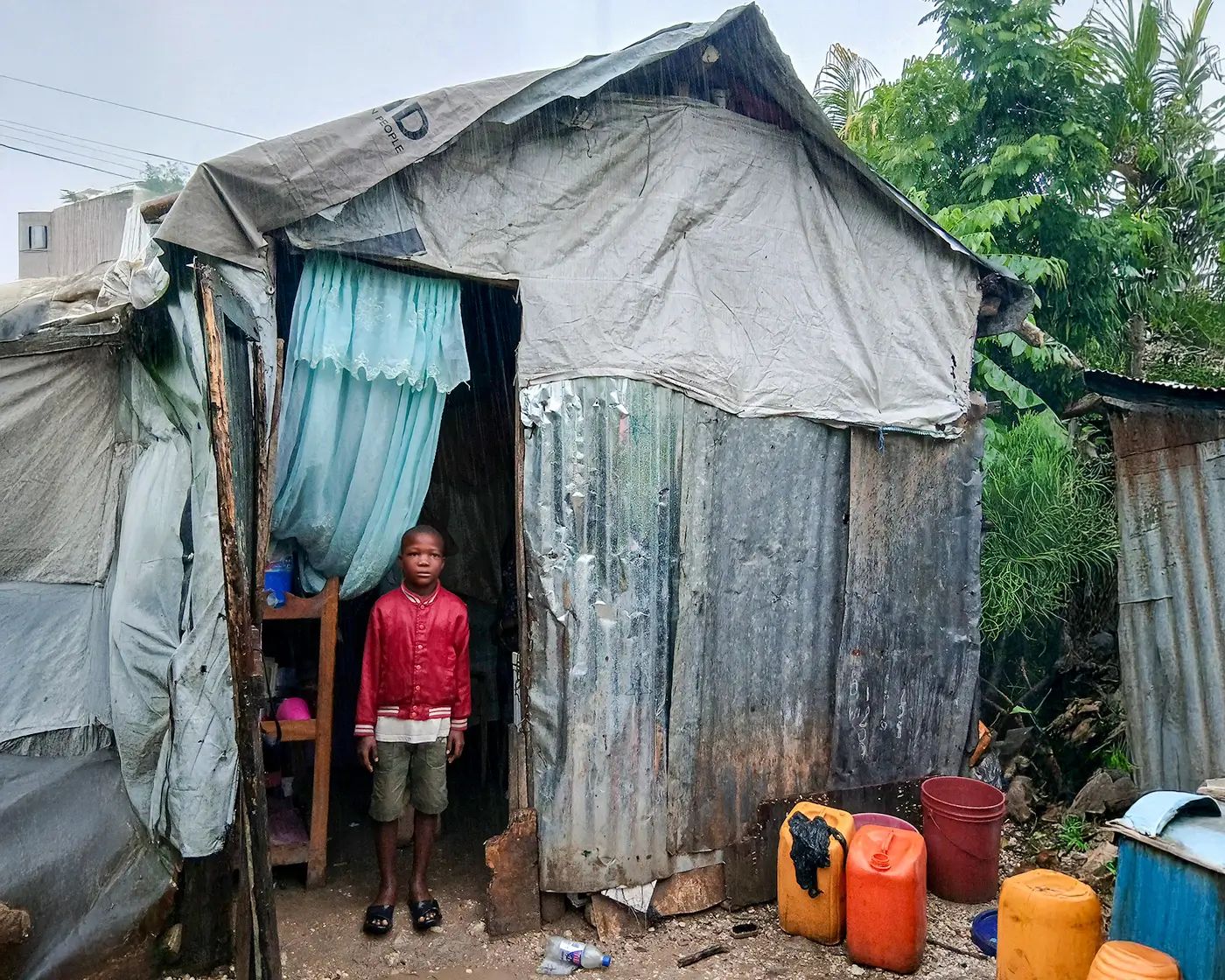 Haitian boy standing at the door of their ramshackle home