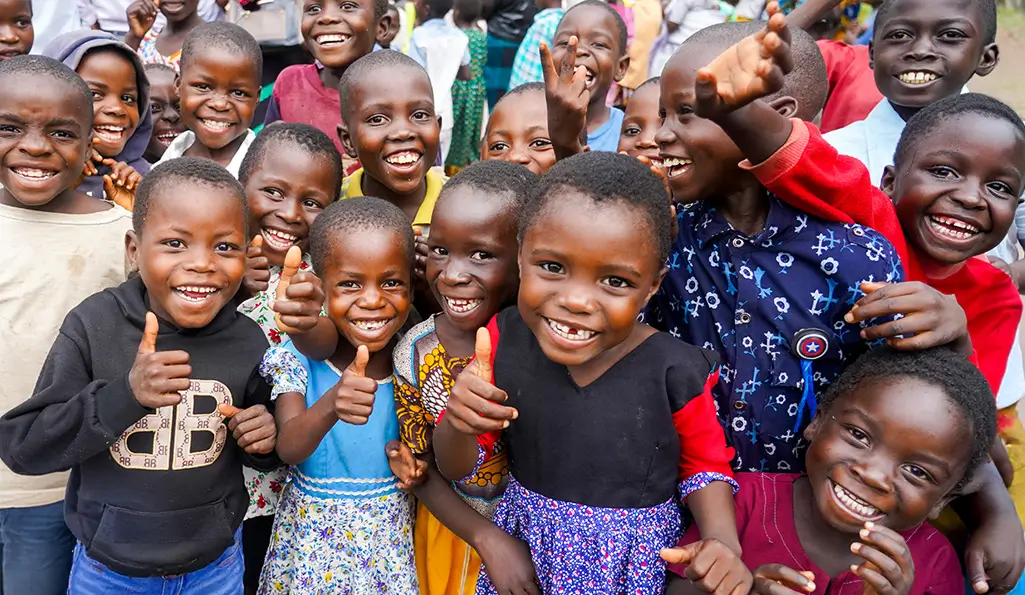 Group of Malawian children smiling and cheering toward the camera.