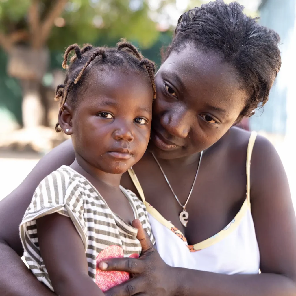 Woman gently embraces a young girl, showing care and closeness.