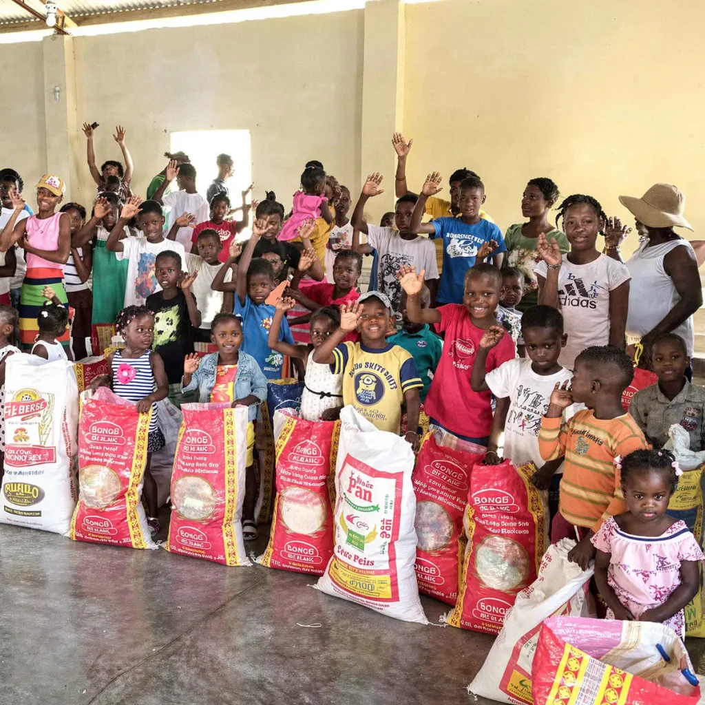 Children and adults gather behind bags of food supplies during a food distribution.